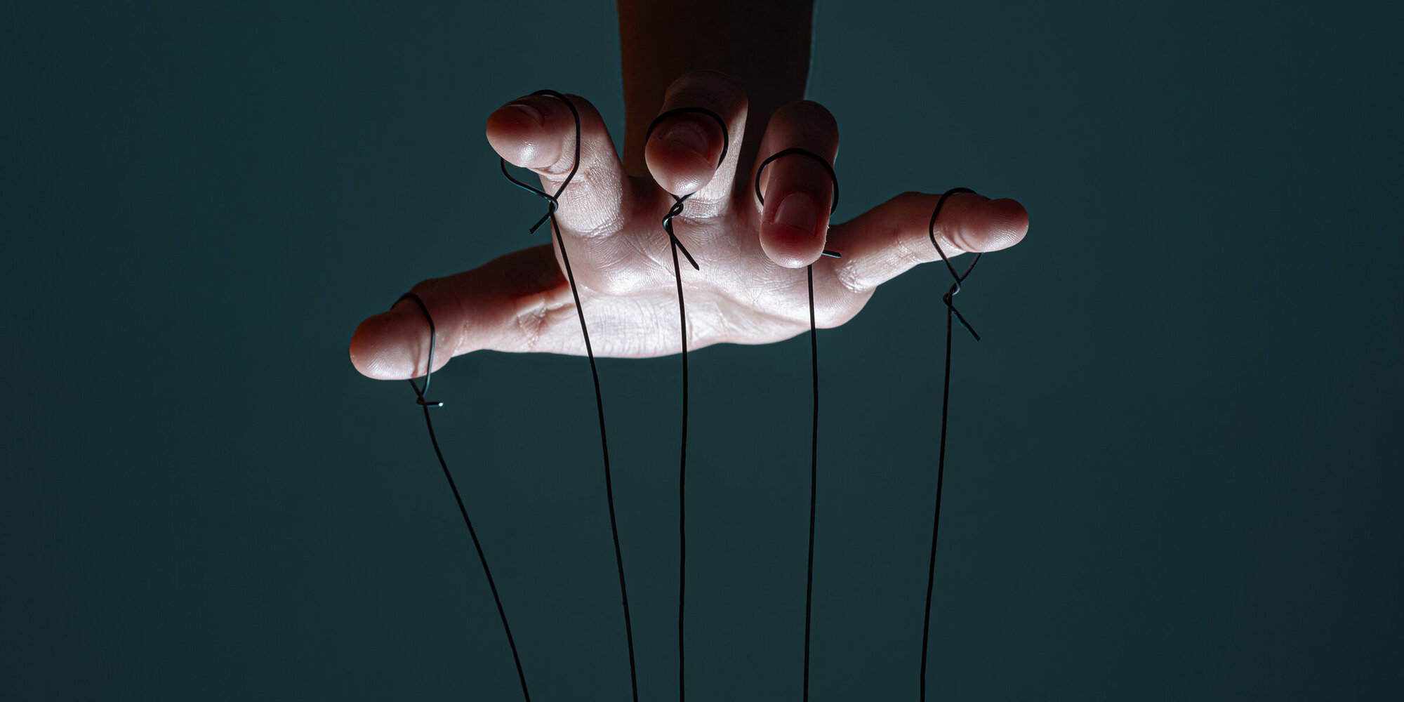Fingers of a puppeteer with strings controlling situation.Concept of manipulation