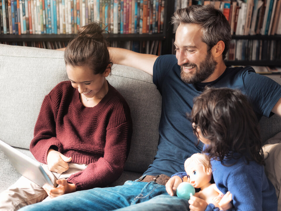 Vater schaut mit seinen kleinen Kindern in ein Laptop