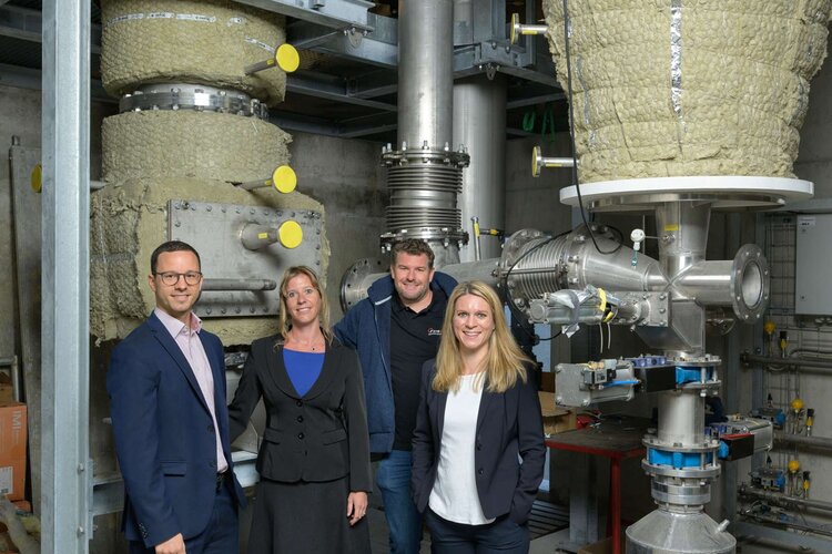Stippvisite auf dem Hof: (v.l.n.r.) Kundenberater Stefan Häusler, Tamara Götz-Graf, Produktmanagerin Umweltdarlehen und Marit Kruthoff, Fachbeauftragte Leistungsaufrag und zuständig für den Nachhaltigkeitsauftrag, besuchten im vergangenen Jahr Landwirt Florian Gut (3. von links), den stolzen Besitzer der pionierhaften Holzenergie-Anlage im Hintergrund. (Bild: Stefan Walter)