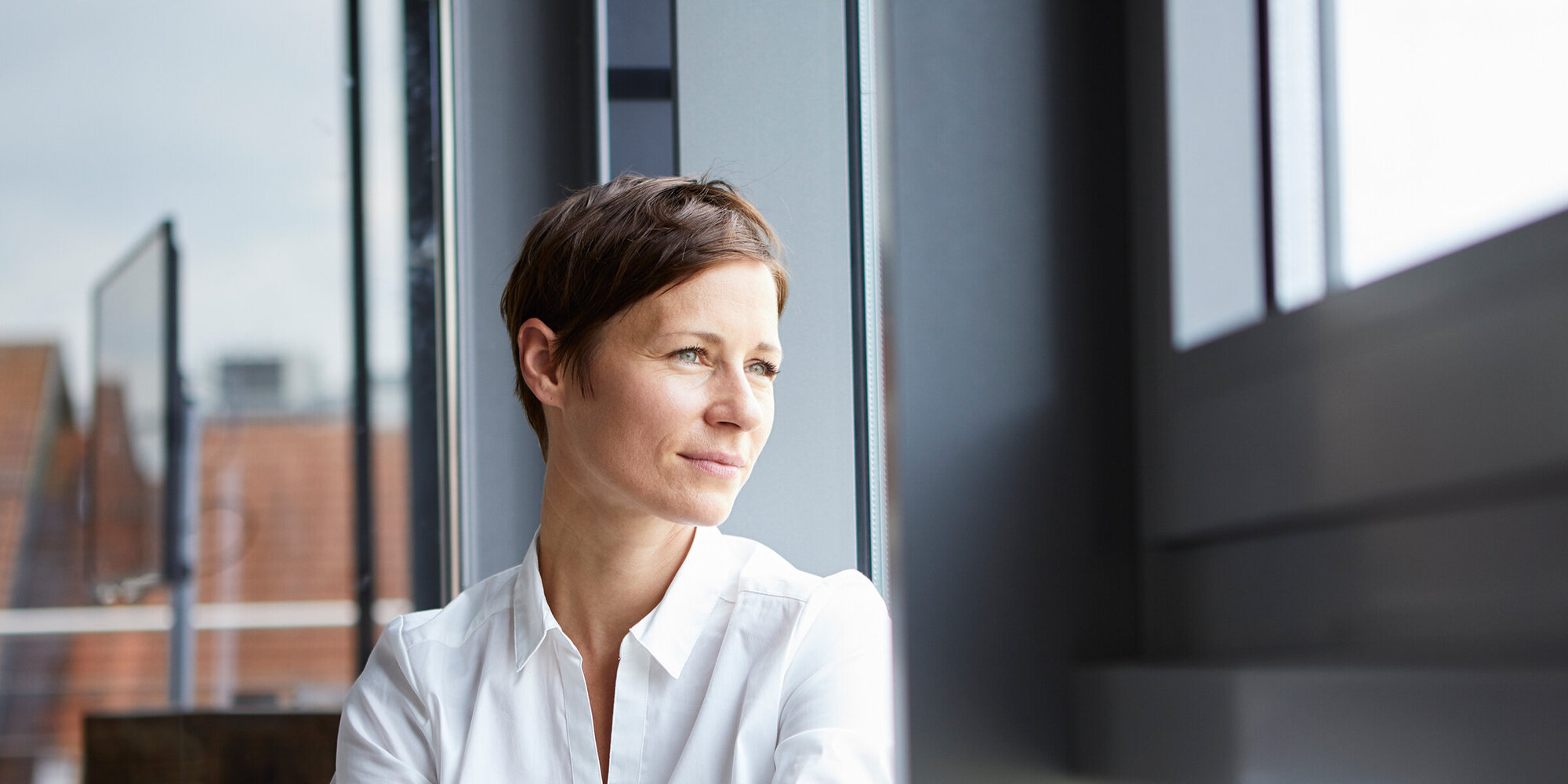 Geschäftsfrau schaut in der Kaffeepause aus dem Fenster