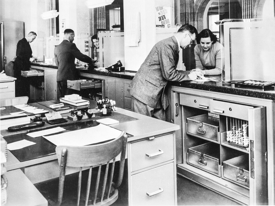 Ein schwarzweiss Bild aus dem Jahr 1950. Es zeigt den Kundenschalter einer Filiale.