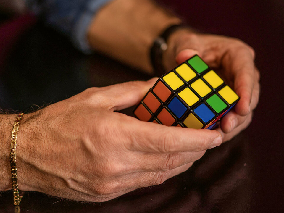 Hände, die einen Rubrik-Würfel bearbeiten